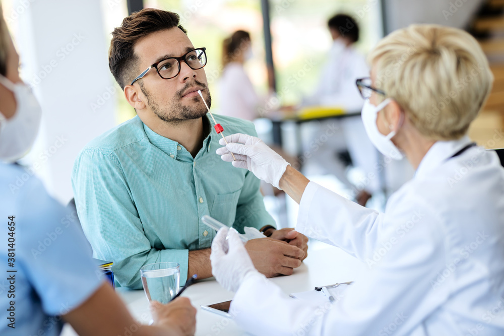 Obraz premium Young man getting tested for coronavirus at medical clinic.