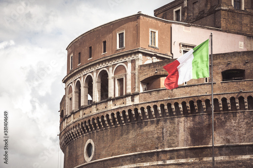Detail of Castel Sant'Angelo Mausoleum of Hadrian in Rome with Italian flag. Ancient and historic castle monument in Italy. Towering cylindrical building.