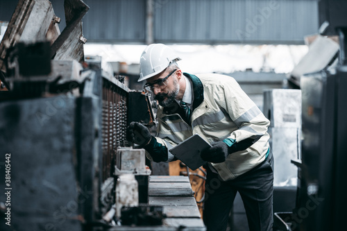 Technicians man or engineer holding tablet for checking work in a heavy industrial factory behind. The Maintenance looking of working at industrial machinery and check security system setup © KPs Photography 