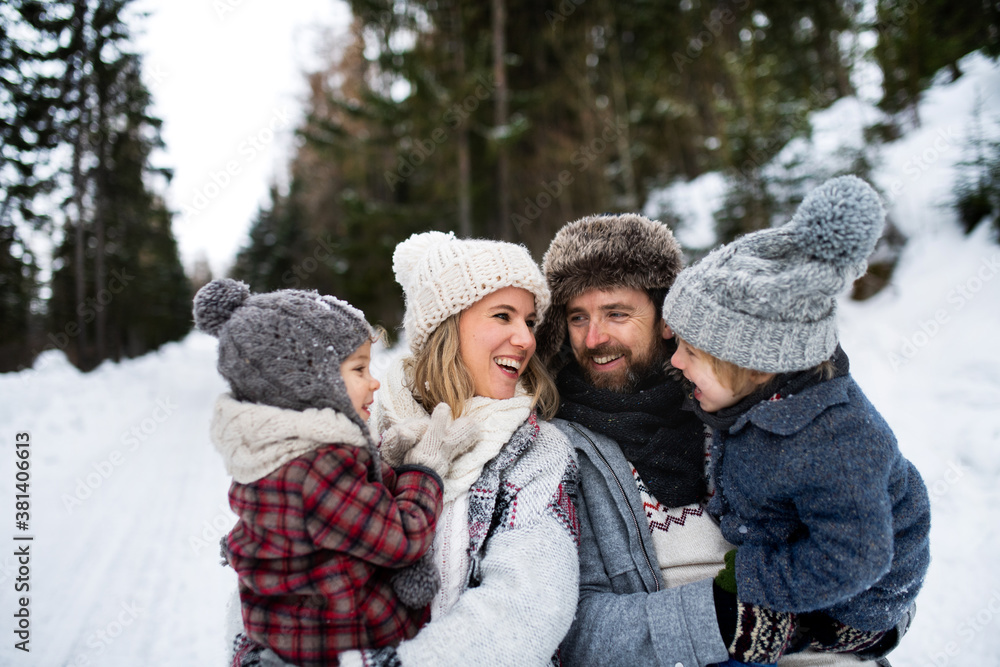 Father and mother with two small children in winter nature, standing in the snow. Father and mother with two small children in winter nature, standing in the snow.