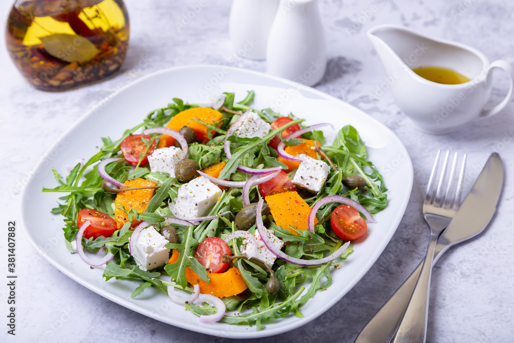 Warm salad with pumpkin, feta cheese, tomatoes, capers, arugula and red onion. Close-up. Warm salad with pumpkin, feta cheese, tomatoes, capers, arugula and red onion. Close-up.