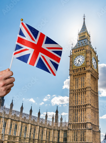 Toursist in London holding flag of Great Britain in hand. Big Ben in background.