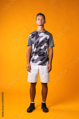 Full length portrait of a young man in sportswear against orange background