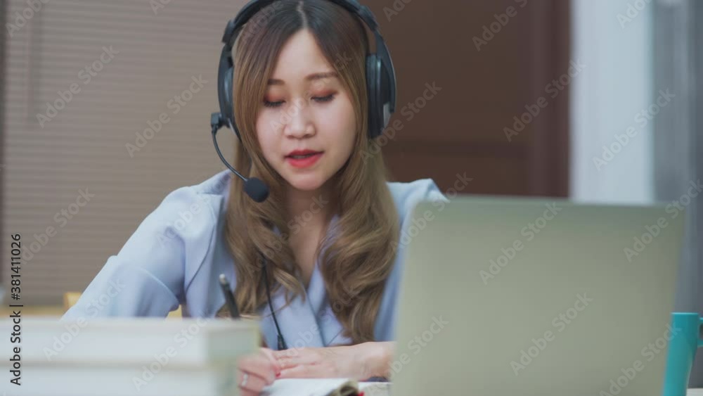 Young Asian woman wearing headset using laptop as webcam working at home, Chinese teenage girl study with computer from internet for new normal distance learning concept. Young Asian woman wearing headset using laptop as webcam working at home, Chinese teenage girl study with computer from internet for new normal distance learning concept.