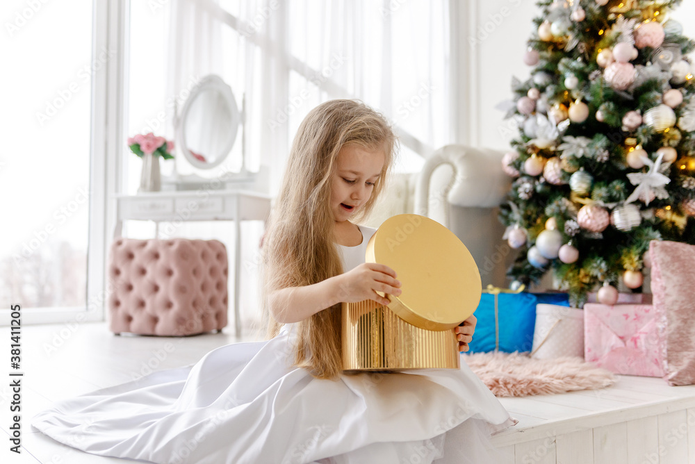 Cute little blonde girl opens a Christmas present. Happy Christmas baby. Cute little blonde girl opens a Christmas present. Happy Christmas baby.