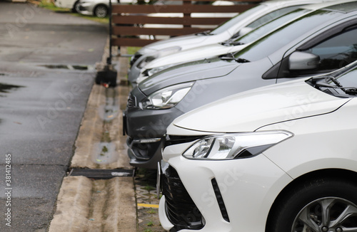 Closeup of front side of white car  with other cars parking in parking area in rainy day. © Amphon