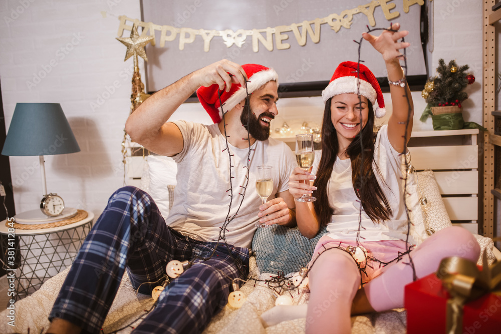 Obraz premium Merry Christmas and Happy New Year! Attractive young couple is celebrating holiday at home together.