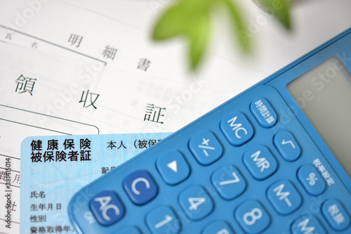 健康保険証、領収証および明細書に電卓と植物あり