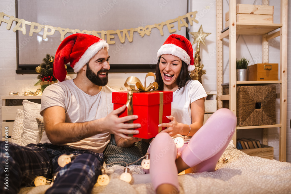 Fototapeta premium Merry Christmas and Happy New Year! Attractive young couple is celebrating holiday at home together.