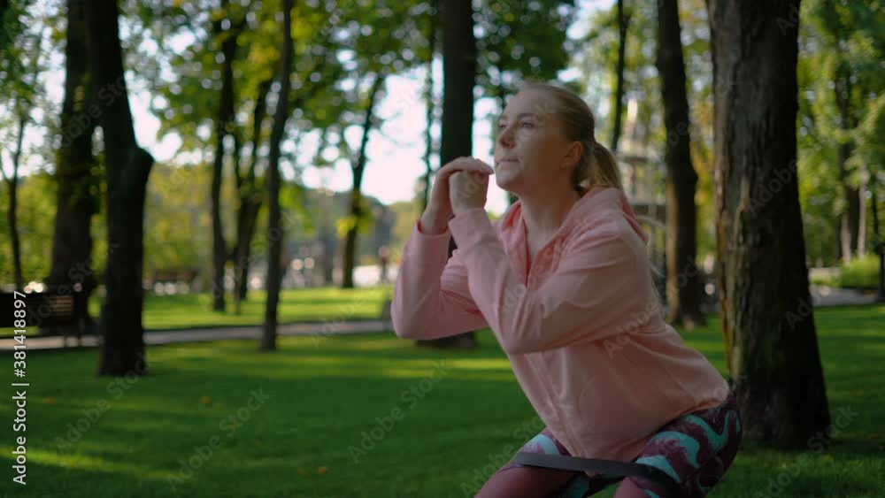 sportive blonde girl doing exercises in the park with a fitness rubber band. 4K sportive blonde girl doing exercises in the park with a fitness rubber band. 4K