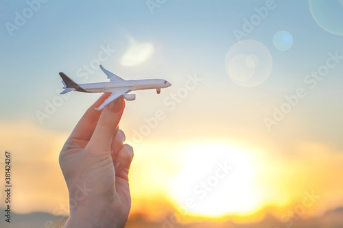 Airplane against sun sky. Woman's hand and plane. Travel, departure, freedom concept. Transport