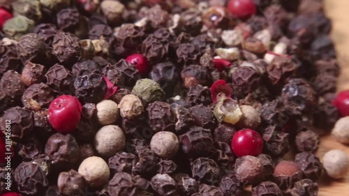 Closeup of a pile of colored peppercorns on a bamboo cutting board. Macro shot. Narrow depth of field.