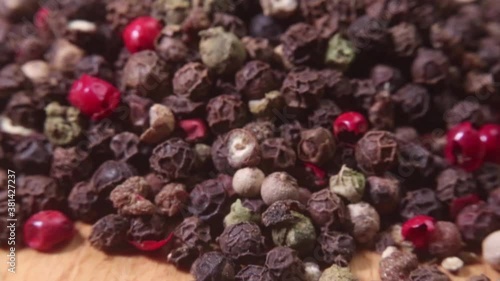 Closeup of a pile of colored peppercorns on a bamboo cutting board. Macro shot. Narrow depth of field.