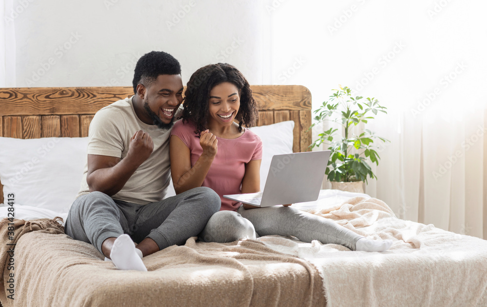 Emotional african american couple looking at laptop screen and screaming Emotional african american couple looking at laptop screen and screaming