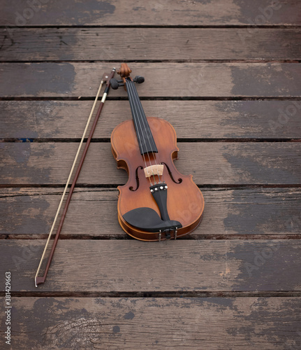 Violin put beside bow on old wooden timber board,show detial of acoustic instrument © Watcharin