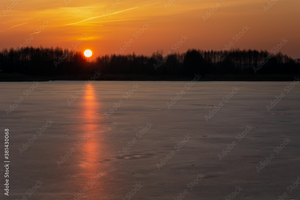 An orange sunset over a frozen lake