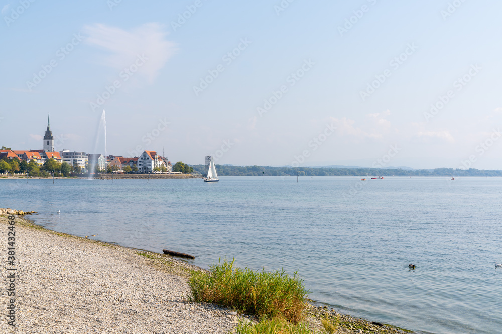 rocky beach on Lake Constance with Friedrichshafen and geyser in the background