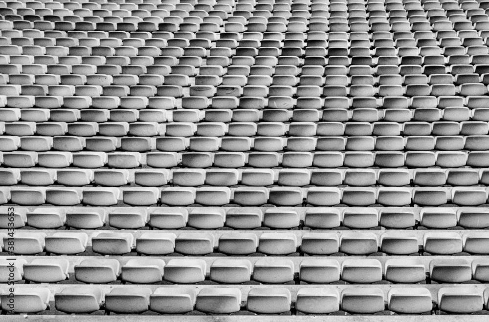 black and white view of endless rows of empty chairs in a stadium