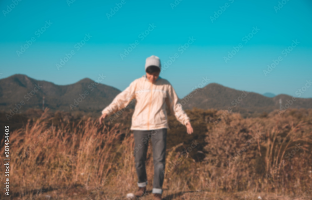 Blur fun Asian young man in Long-sleeved shirt and grey hat hiking standing at mountain peak above clouds  Hiker outdoor. Maetip Reservoir Lamphun Province, Northern Thailand Province in the morning.