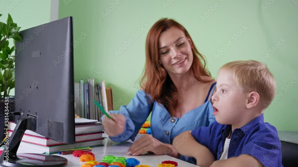 pupil homeschooled, schoolboy with down syndrome doing school homework with female teacher using computer at room during a pandemic pupil homeschooled, schoolboy with down syndrome doing school homework with female teacher using computer at room during a pandemic