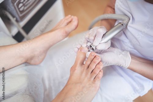 Hardware medical pedicure with nail file drill apparatus. Patient on pedicure treatment with pediatrician chiropodist. Foot peeling treatment at spa with a special device. Clinic of Podiatry Podology