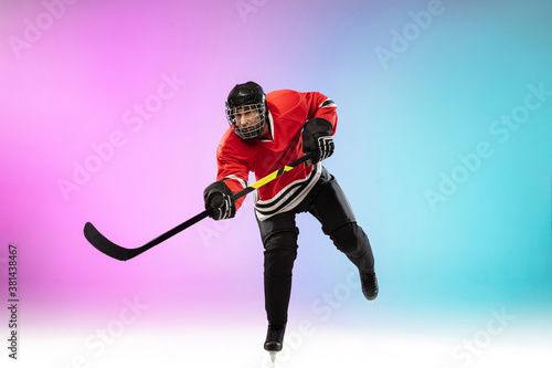 On the run. Male hockey player with the stick on ice court and neon gradient background. Sportsman wearing equipment, helmet practicing. Concept of sport, healthy lifestyle, motion, wellness, action.