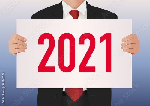 Pour présenter le bilan de son entreprise, un cadre dirigeant en costume cravate, porte une pancarte blanche sur lequel est écrit l’année 2021