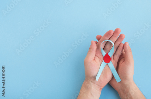 Wallpaper Mural World diabetes day. Man hands hold light blue ribbon awareness with red blood drop. Top view, copy space Torontodigital.ca