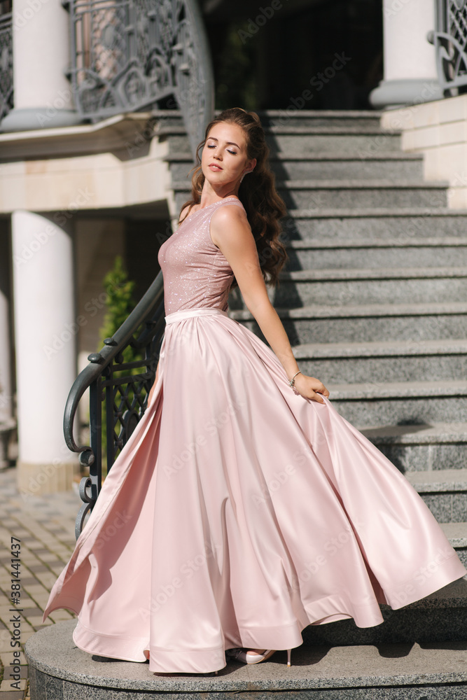 Beautiful girl with curly hair in evening dress stand on the stairs Beautiful girl with curly hair in evening dress stand on the stairs