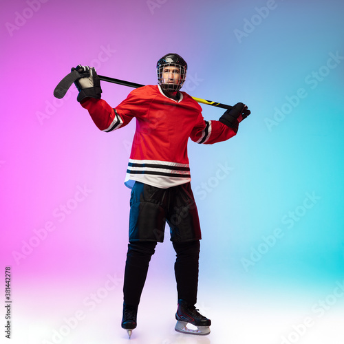 Leader. Male hockey player with the stick on ice court and neon gradient background. Sportsman wearing equipment, helmet practicing. Concept of sport, healthy lifestyle, motion, wellness, action. © master1305