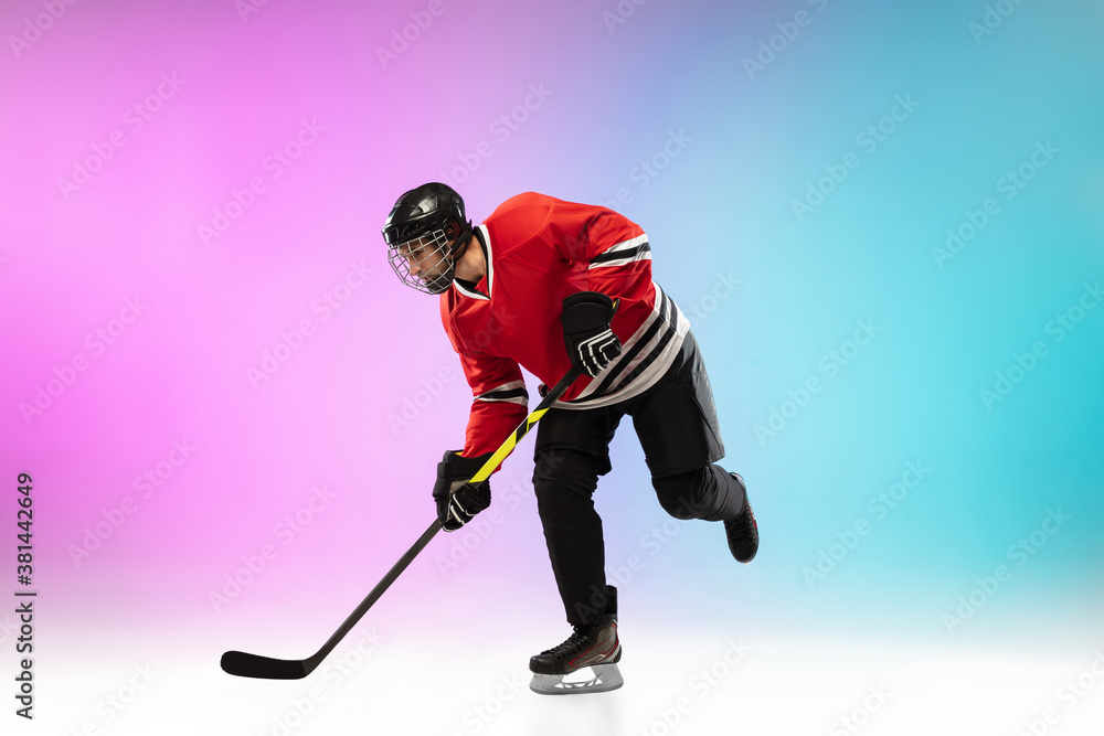 Obraz premium Goal. Male hockey player with the stick on ice court and neon gradient background. Sportsman wearing equipment, helmet practicing. Concept of sport, healthy lifestyle, motion, wellness, action.