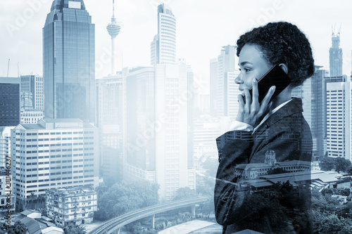 Photography Successful smiling black African American business woman in suit pensively talking phone, Kuala Lumpur cityscape