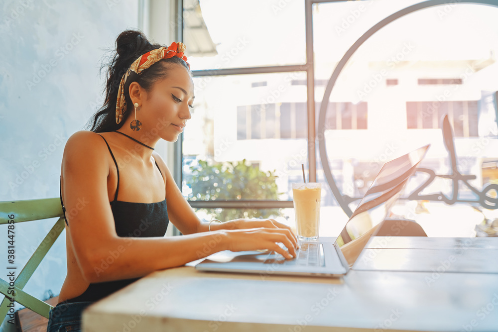 a young asian woman using her laptop in cafe