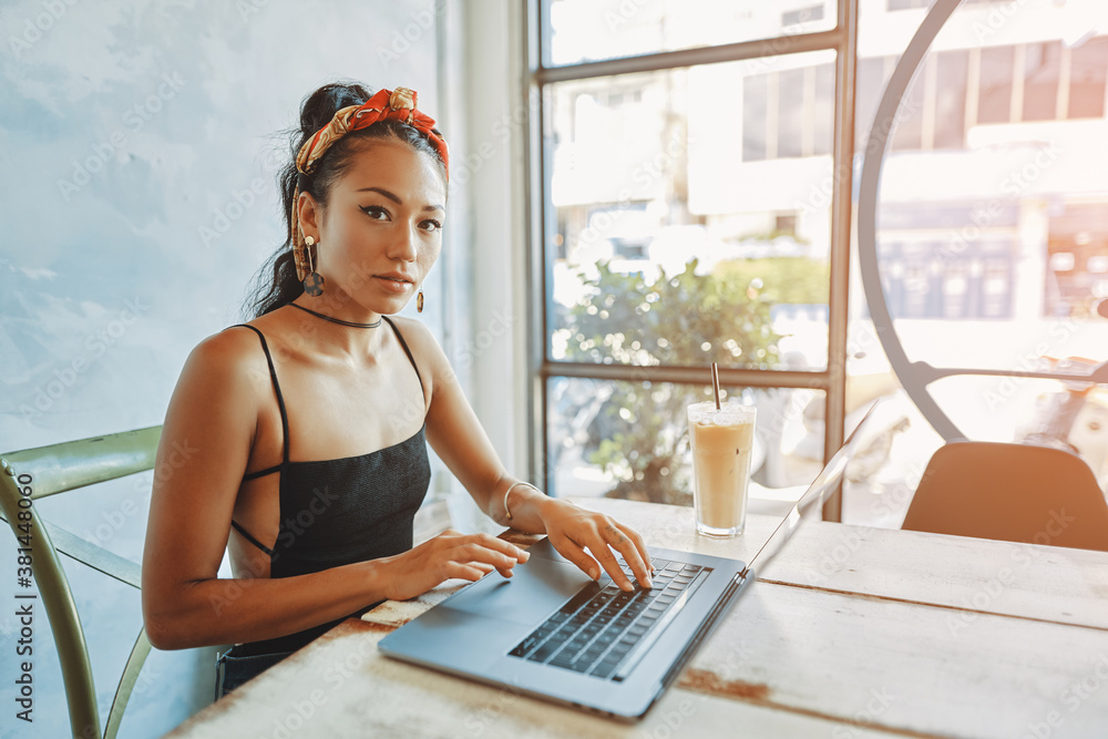 a young asian woman using her laptop in cafe
