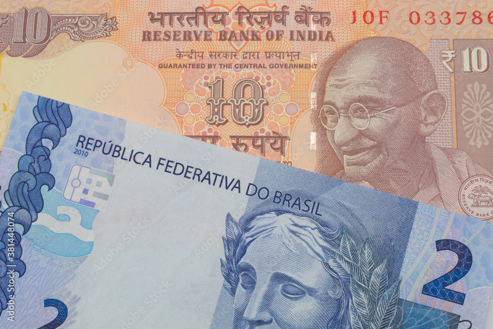 A macro image of a orange ten rupee bill from India paired up with a blue two real bank note from Brazil.  Shot close up in macro.