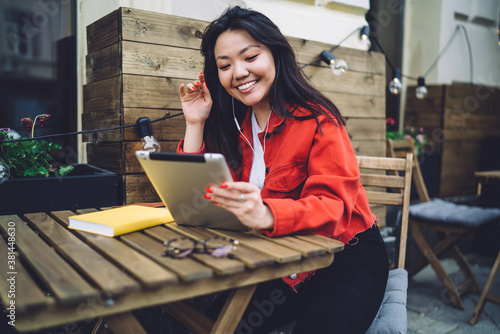 Photography Cheerful young female in cafe using tabet for video call