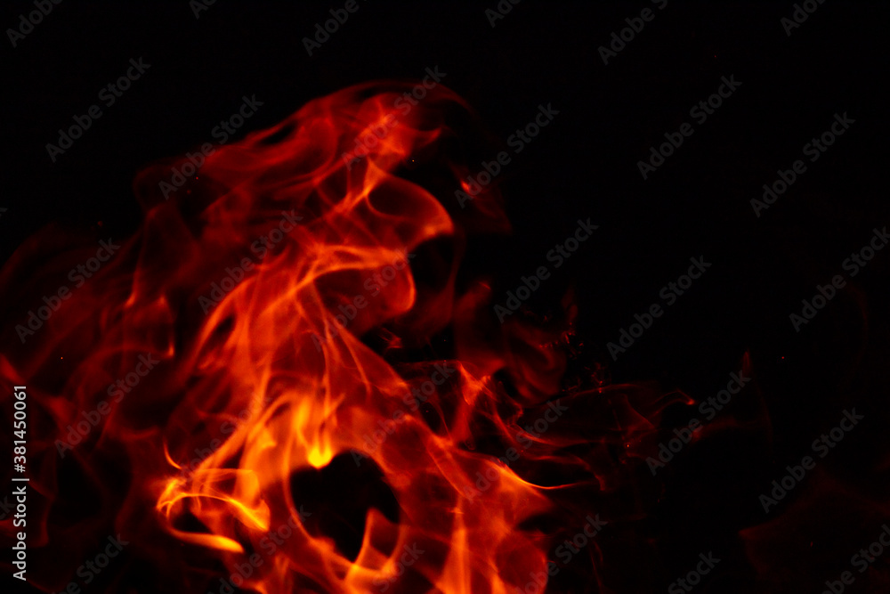 Abstract glowing background. Flames on a dark background with sparks and smoke. Abstract glowing background. Flames on a dark background with sparks and smoke.