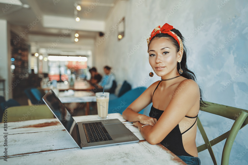 a young asian woman using her laptop in cafe