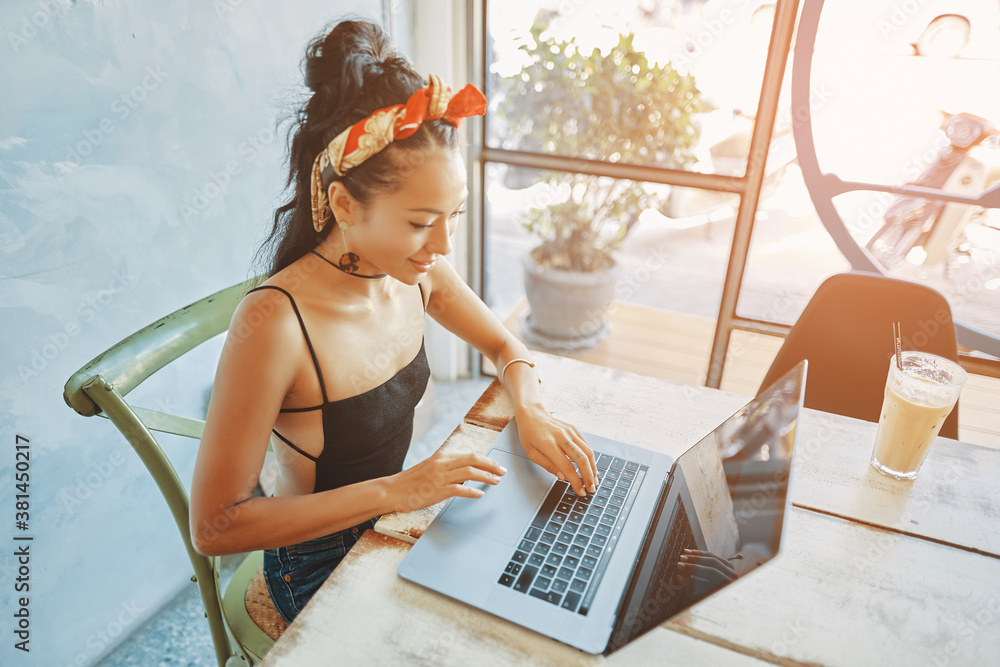 a young asian woman using her laptop in cafe