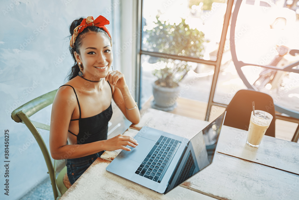 a young asian woman using her laptop in cafe