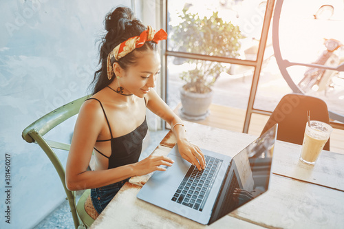 a young asian woman using her laptop in cafe
