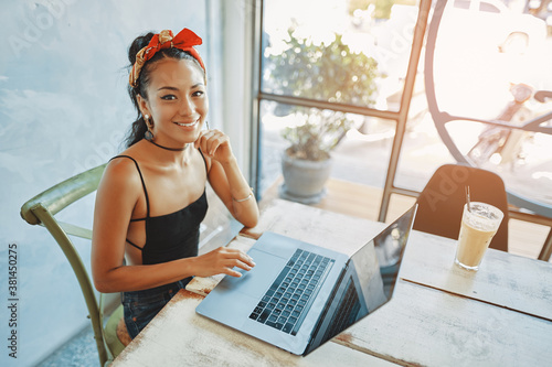 a young asian woman using her laptop in cafe