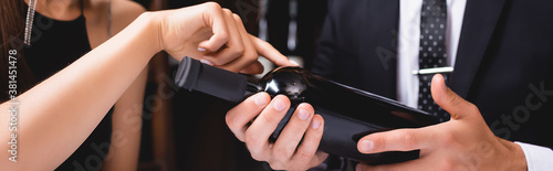 Website header of woman pointing at bottle of wine near boyfriend in suit in restaurant