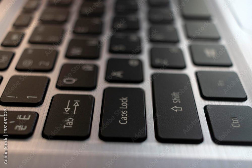 Laptop computer keyboard close up. Black English Russian letters on a metal background. Laptop computer keyboard close up. Black English Russian letters on a metal background.