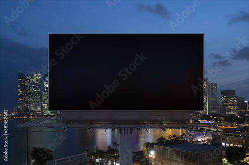 Blank black road billboard with Singapore cityscape background at night time. Street advertising poster, mock up, 3D rendering. Front view. The concept of marketing communication to sell idea. © VideoFlow