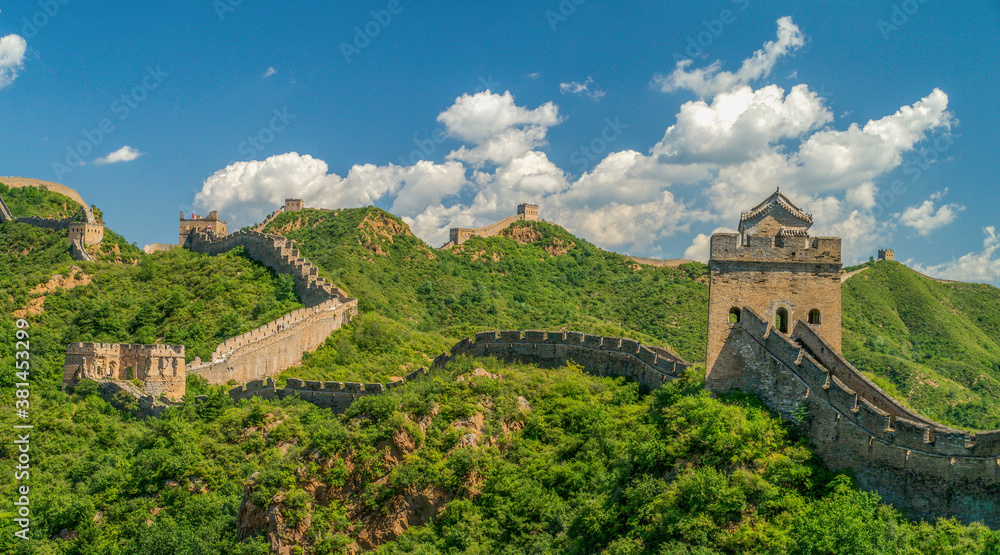 Panorama photo of Great Wall in China winding over the mountains with beautiful sky above