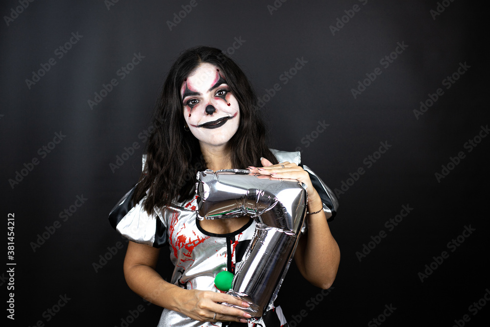 Obraz premium woman in a halloween clown costume over isolated black background holding a number seven balloon. Anniversary