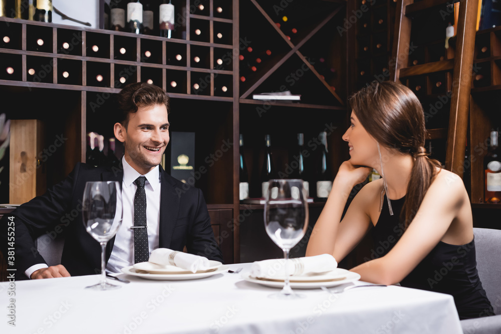Selective focus of young couple looking at each other during dating in restaurant Selective focus of young couple looking at each other during dating in restaurant