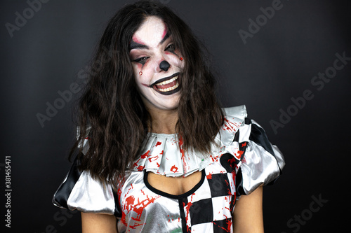 Canvas-taulu woman in a halloween clown costume over isolated black background doing crazy fa