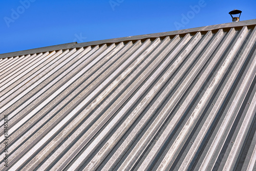Texture of the roof of a house assembled from galvanized iron sheets against a blue sky